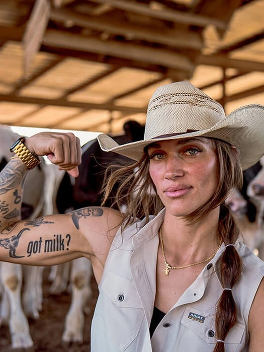Dairy farmer flexing her arm to show a “got milk?” tattoo