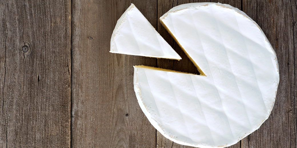 A wheel of Brie cheese with a slide cut out