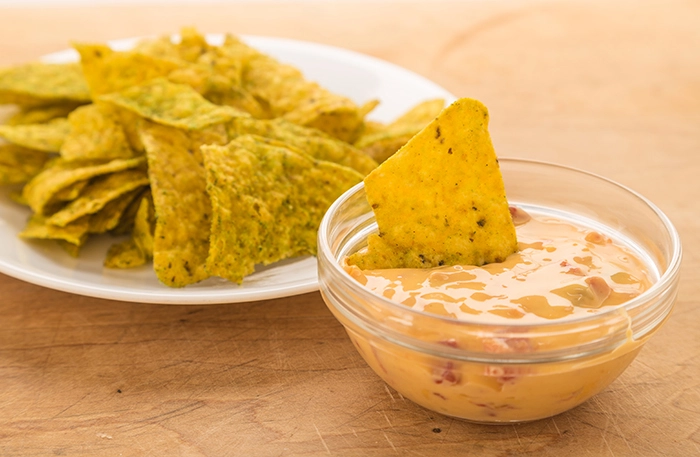Cheese dip served alongside a plate of tortilla chips.