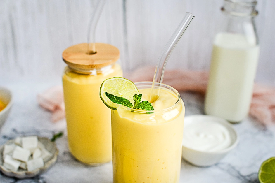 Tropical smoothie served in 2 glasses garnished with fresh lime and mint