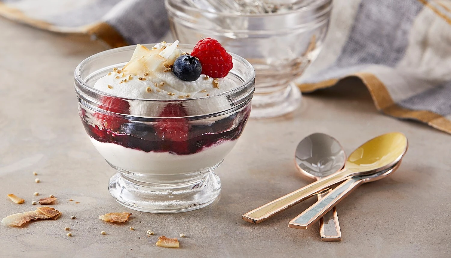 Clear dish of yogurt garnished with berries and coconut flakes